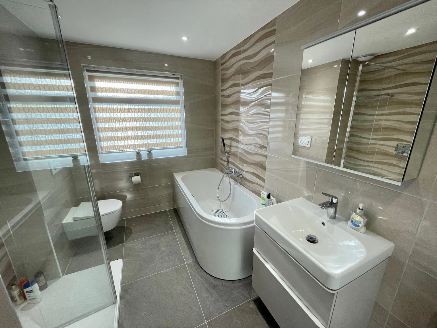 Beige bathroom renovation with new bath tub, shower enclosure, sink and W/C